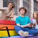 Three teenagers sat on a park bench