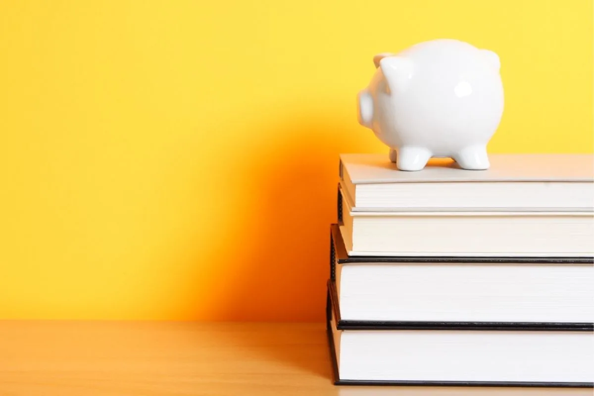 White piggy bank on books with a bright yellow background