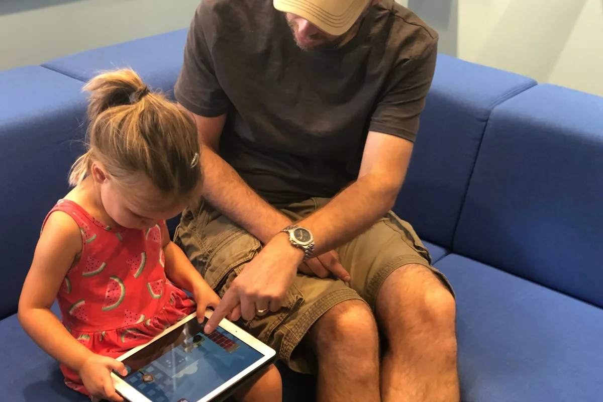 Child and father playing iPad