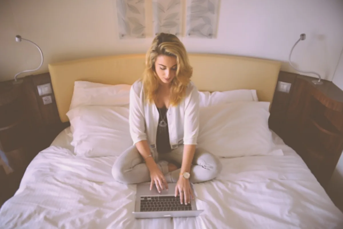 Lady on a bed looking at laptop