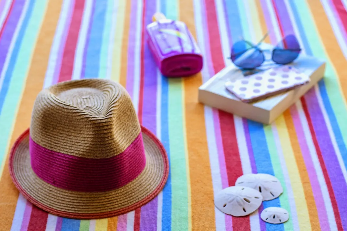 Hat, book and sandglasses on a picnic blanket