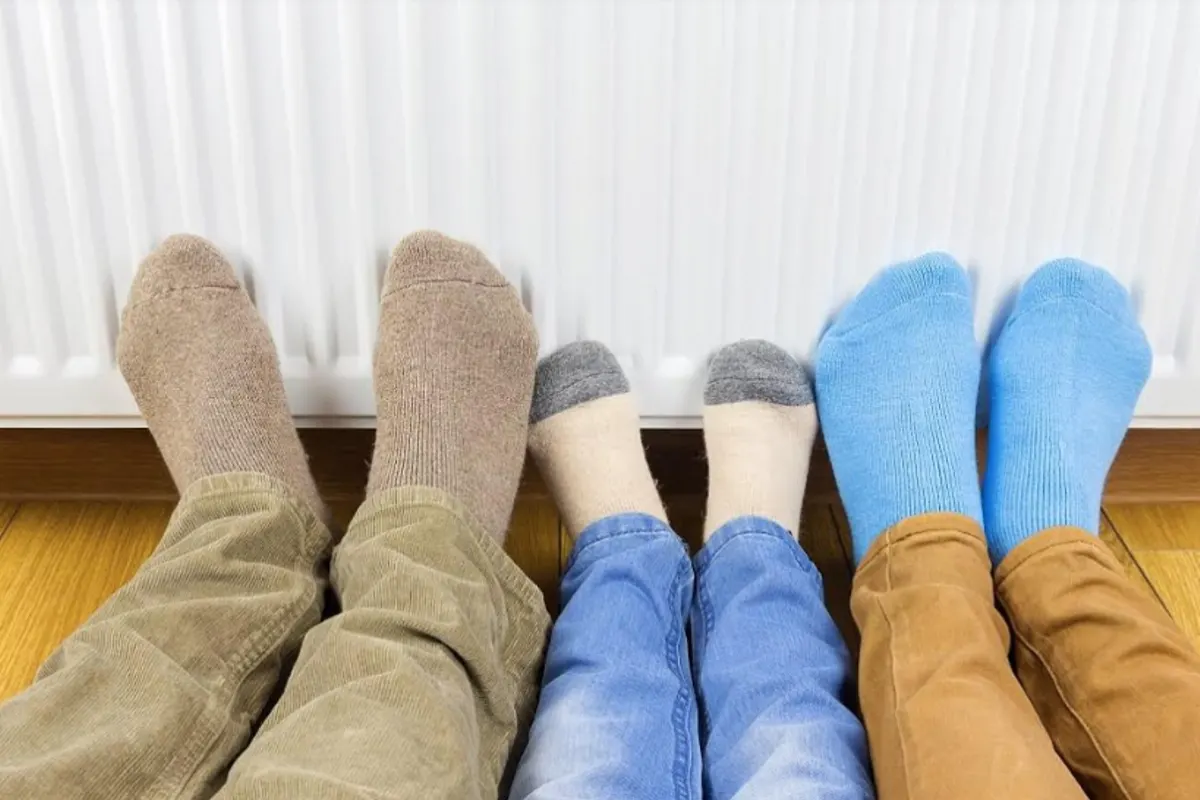 three sets of feet touching a radiator