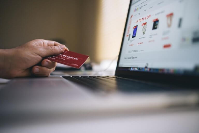 Man holding a credit card against a laptop