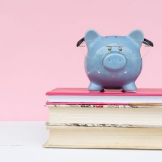 pink background with a blue pig on top of books