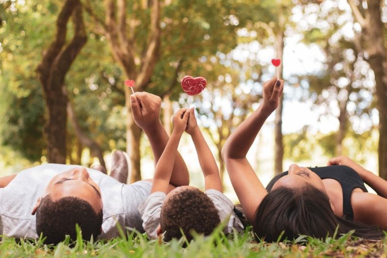 Two adults and a child paying down holding a heart lollypop