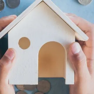 Hands holding a small house