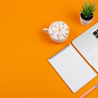 Orange background with notepad and laptop
