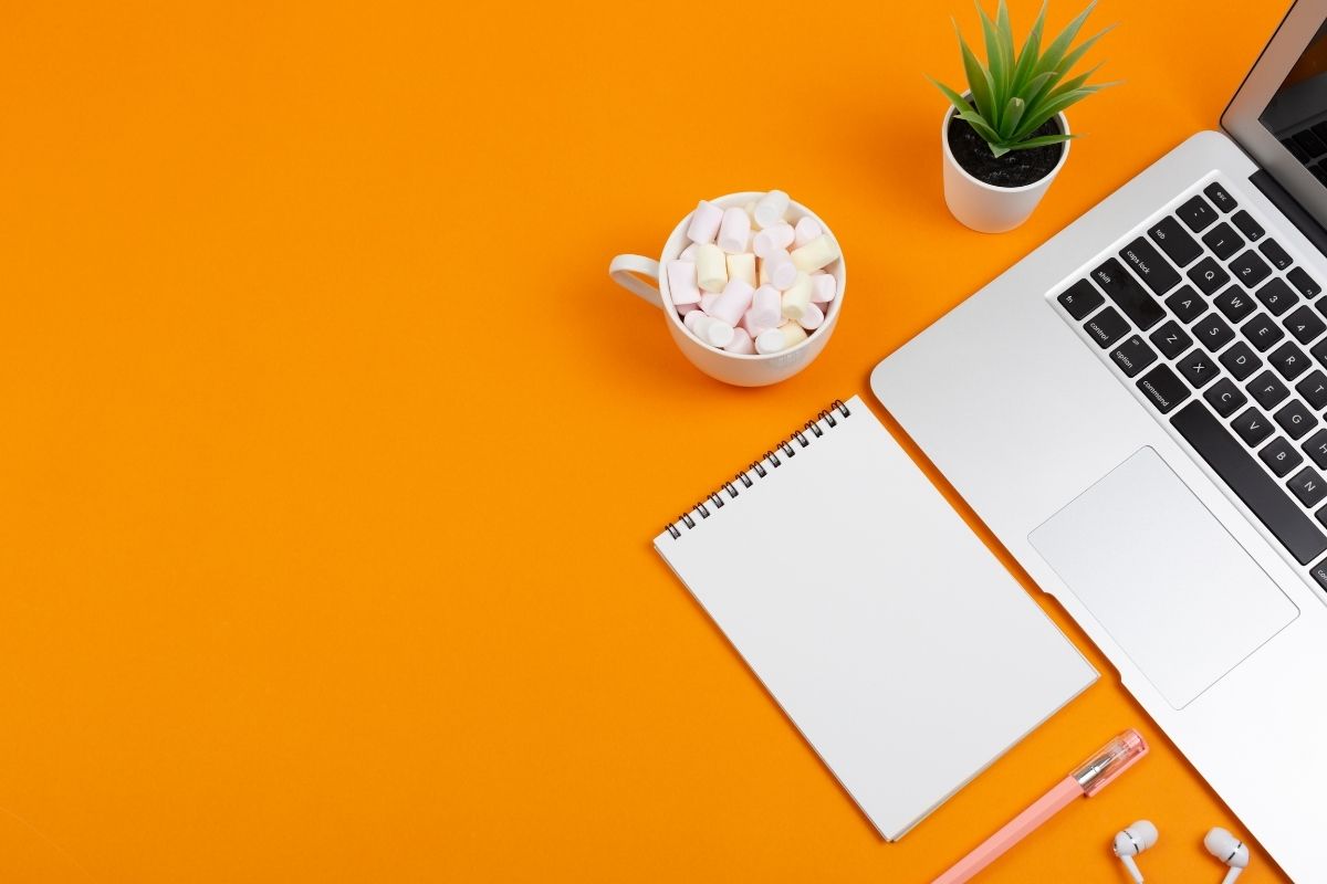Orange background with notepad and laptop